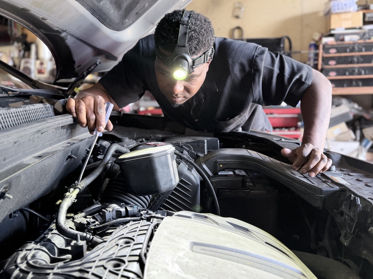 Omari Grant inspecting a vehicle engine at Front Line Auto